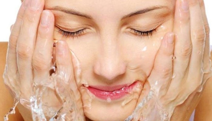 Woman washing face with soap